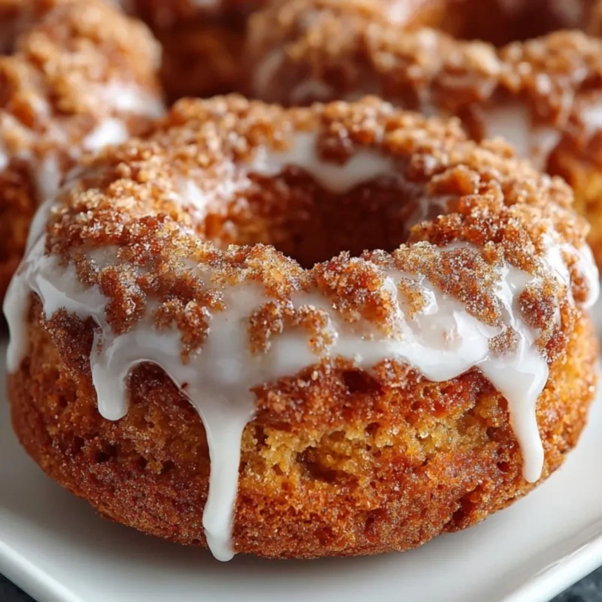 Golden, glazed spiced apple cider donuts, smelling of cinnamon and nutmeg, ready to eat.