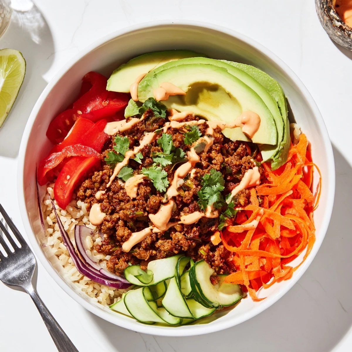 Savory plant-based meat bowl garnished with avocado, lime, and cherry tomatoes.  
