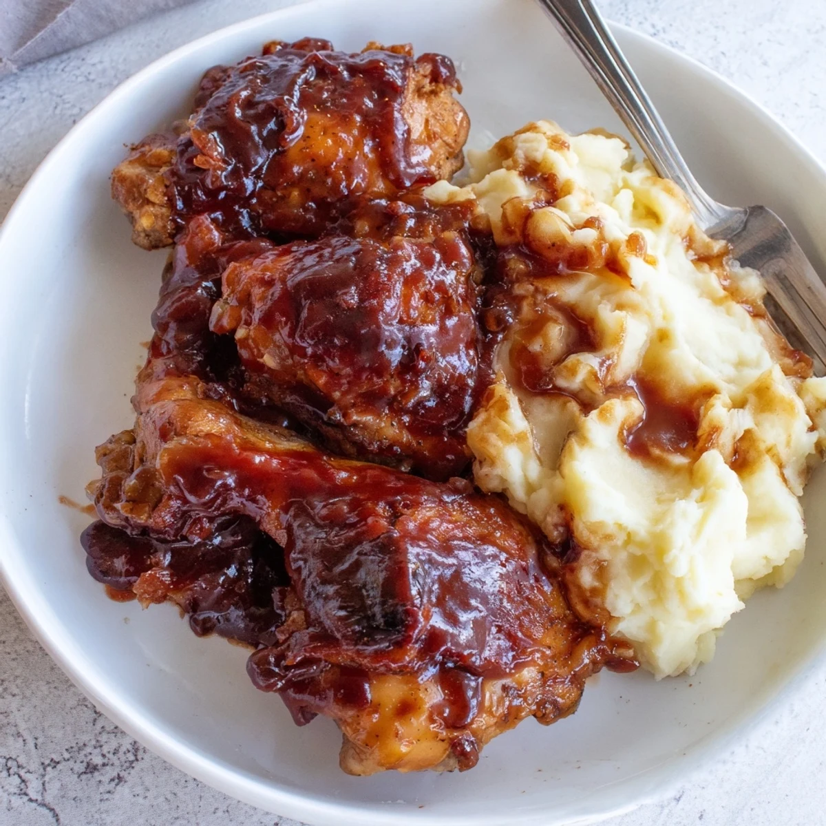 Succulent honey BBQ chicken thighs paired with creamy garlic mashed potatoes on a plate.  