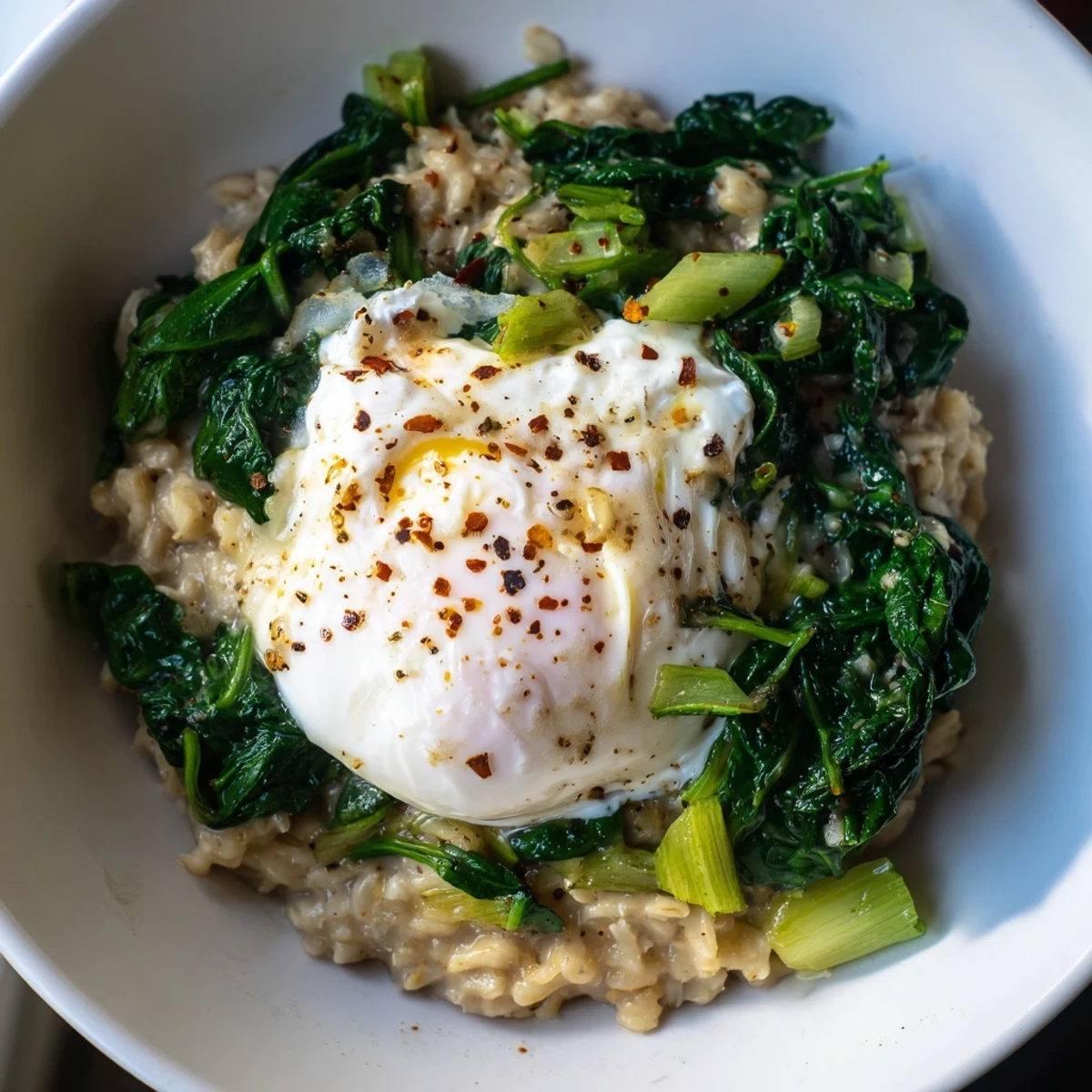 Enjoy this creamy bowl of Savoury Oatmeal with Spinach & Poached Egg topped with parmesan cheese.