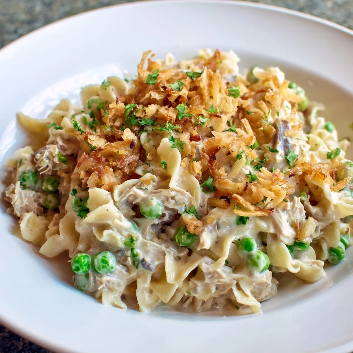 A close-up of creamy Tuna Noodle Casserole, topped with crunchy fried onions, ready to be served.