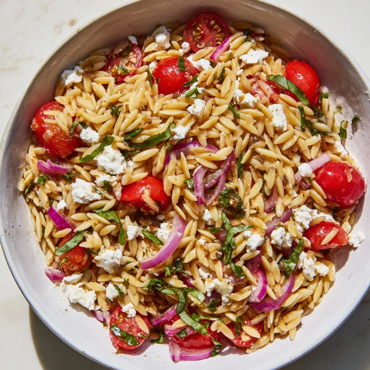 Creamy feta cheese glistening over a bowl of Tomato Feta Orzo, a perfect vegetarian option.