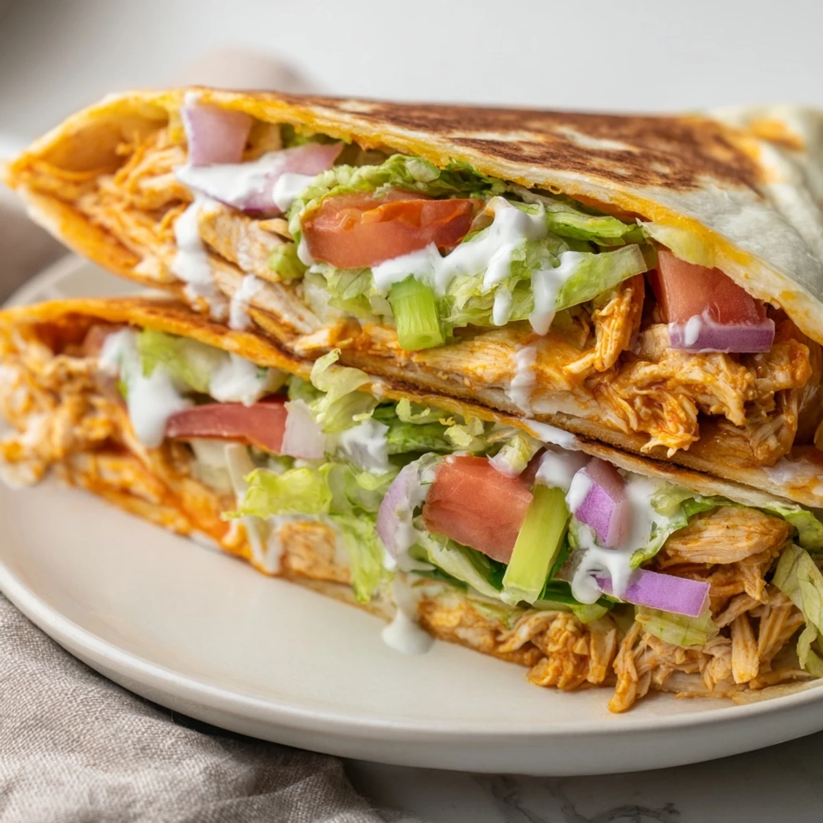 Textured, folded buffalo chicken wrap, bursting with veggies and melted cheddar cheese.