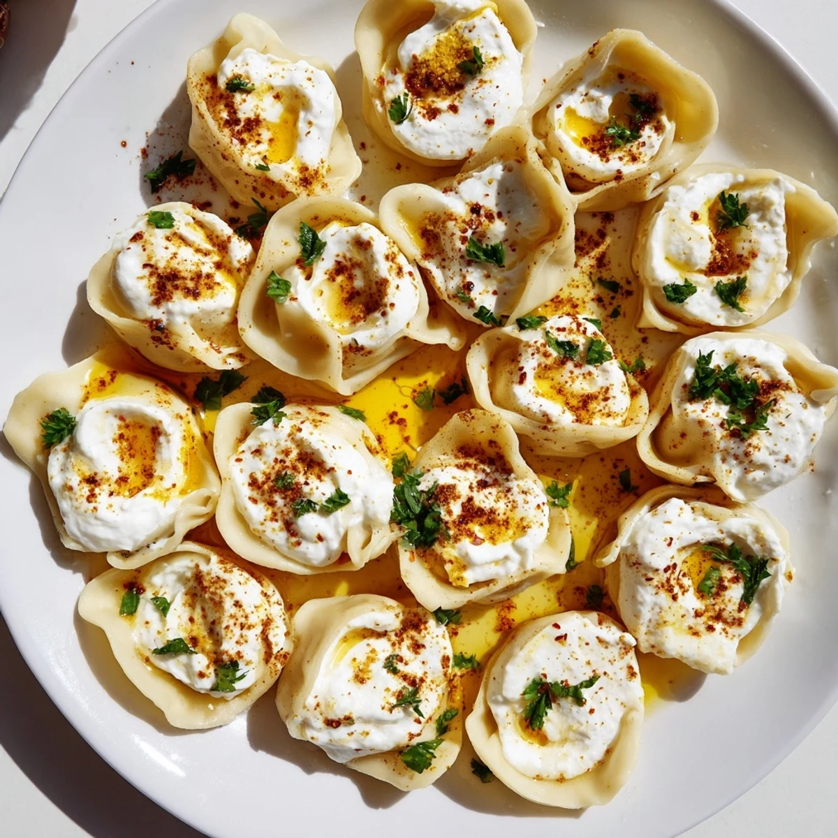 Close-up of golden-brown Turkish Cheesy Manti, freshly cooked and served with a flavorful yogurt sauce.  