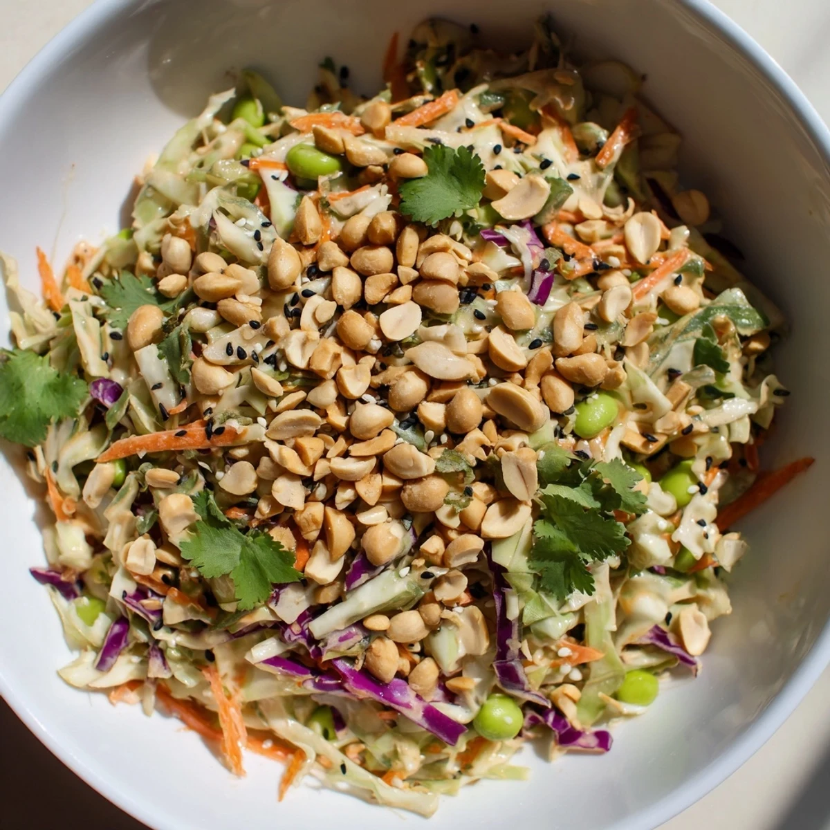 Shredded cabbage, carrots, and edamame glisten in a creamy peanut dressing for this vibrant Crunchy Thai Peanut Salad.
