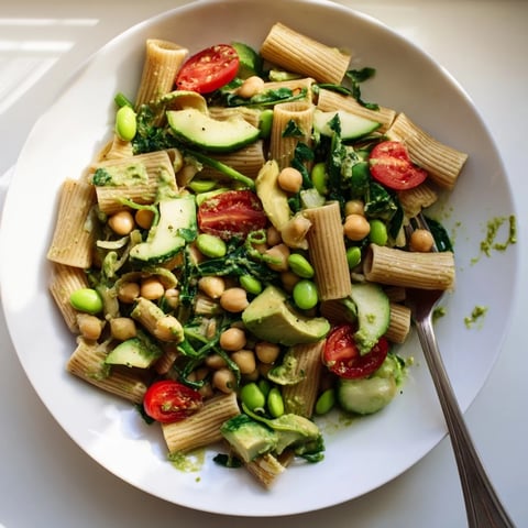 Holiday Glow Green Goddess Protein Pasta Salad, a colorful bowl with creamy green dressing and fresh vegetables.