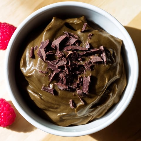 Smooth and luscious avocado chocolate pudding: a healthy dessert topped with fresh berries and shaved chocolate.