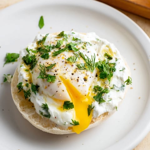 Çılbır Eggs Benedict: creamy poached eggs atop garlicky yogurt and toasted muffins, ready to eat.