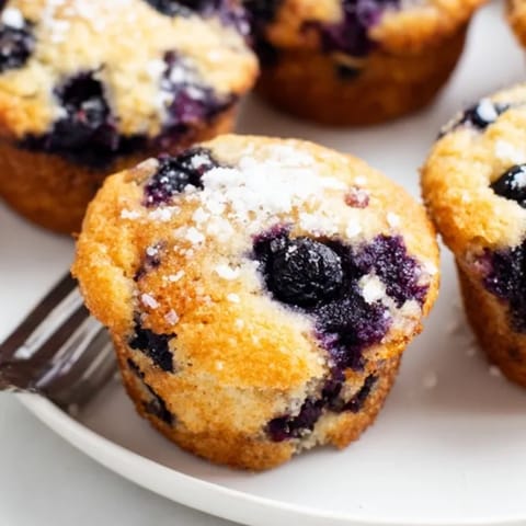 Perfectly domed Blueberry Muffins, speckled with juicy berries, served for a tasty brunch.