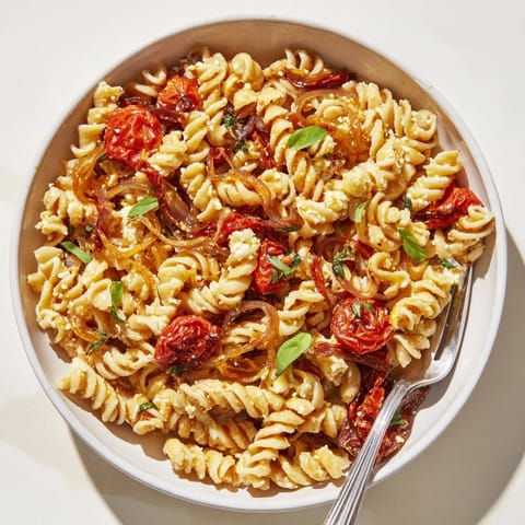 Baked feta pasta dish featuring golden cheese and vibrant roasted cherry tomatoes.  