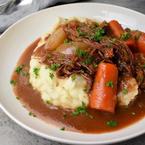 Tender slow cooker pot roast served with creamy mashed potatoes and savory gravy.  