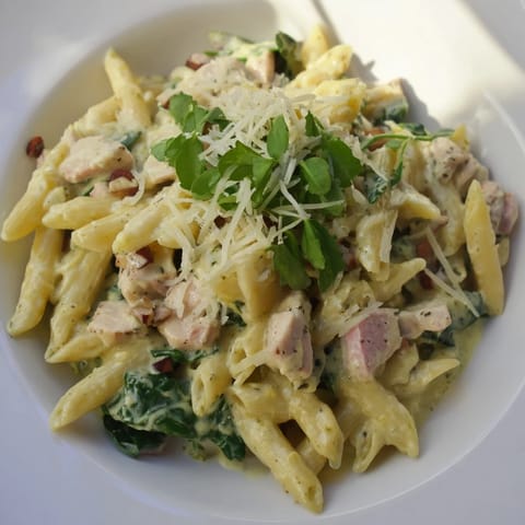 A close-up of One-Pot Creamy Spinach & Turkey Christmas Pasta, creamy sauce highlights the colorful ingredients.