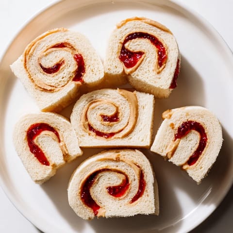 Freshly cut peanut butter and jelly pinwheel rolls, a colorful and fun simple sandwich snack.