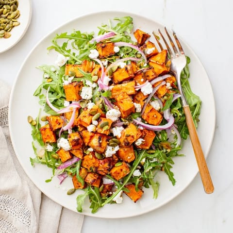 Warm roasted sweet potato salad served over peppery arugula with feta and crunchy seeds.