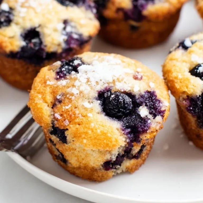 Perfectly domed Blueberry Muffins, speckled with juicy berries, served for a tasty brunch.