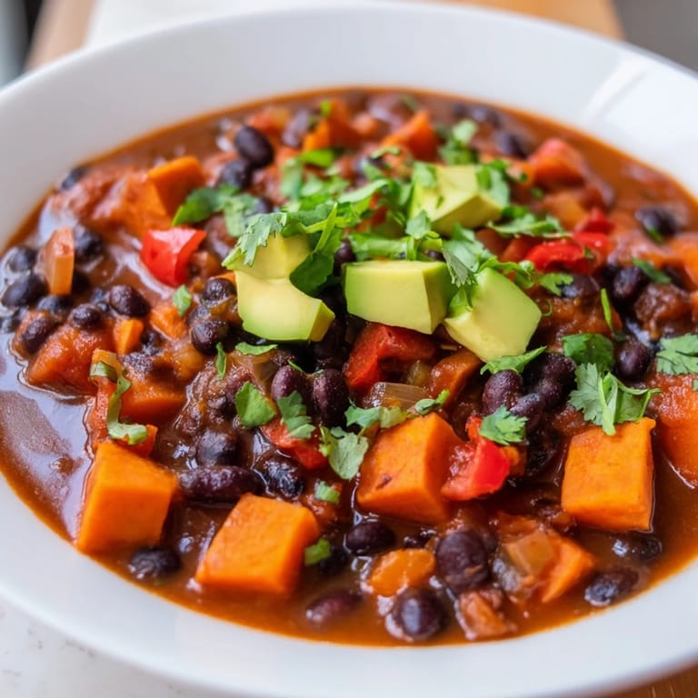 A close-up shot of the flavorful Sweet Potato & Black Bean Chili simmering in a large pot on the stove.